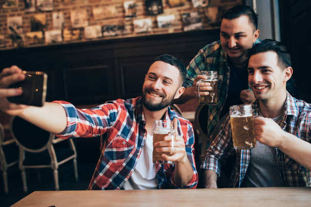 ευτυχισμένος αρσενικούς φίλους λήψη selfie και πίνοντας μπύρα στο μπαρ ή παμπ - Φωτογραφία, εικόνα