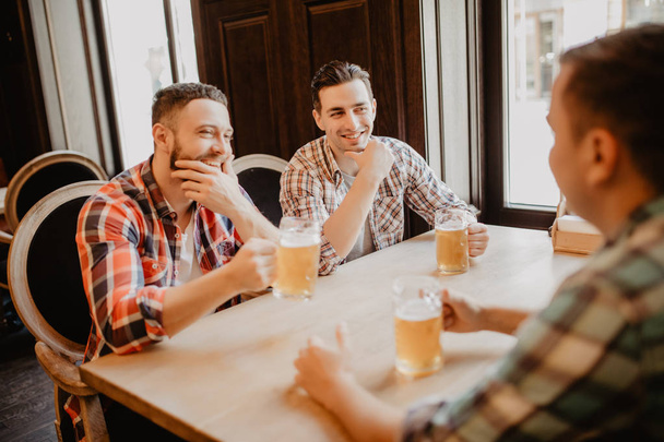 Amigos alegres divirtiéndose y bebiendo cerveza de barril en el pub
. - Foto, Imagen