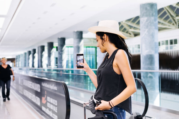 Woman with smartphone at airport. Young traveler checking boarding time with mobile phone app in terminalstation. Tourist on vacation, - Foto, Imagem