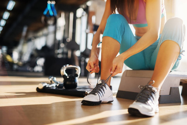жінка обв'язує шнурки в спортзалі
 - Фото, зображення