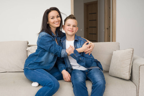 Portrait of mother and her son on sofa at home - Фото, изображение