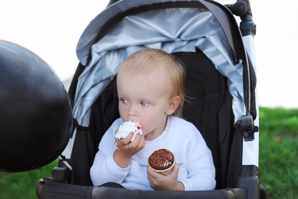 Şirin bebek kız bebek arabası içinde lezzetli kek yiyor       - Fotoğraf, Görsel