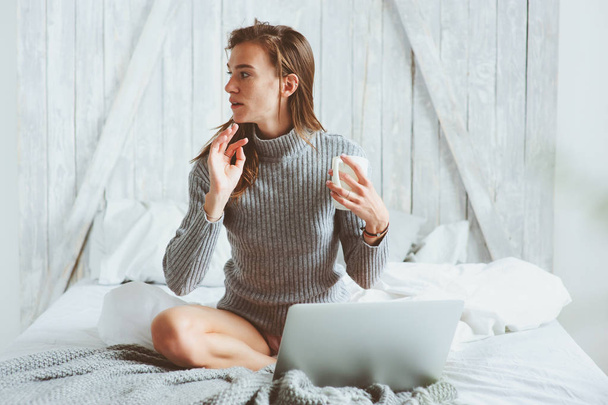 young blogger or business woman working at home with social media, drinking coffee in early morning in bed. Modern living in scandinavian interior, casual lifestyle - Fotoğraf, Görsel