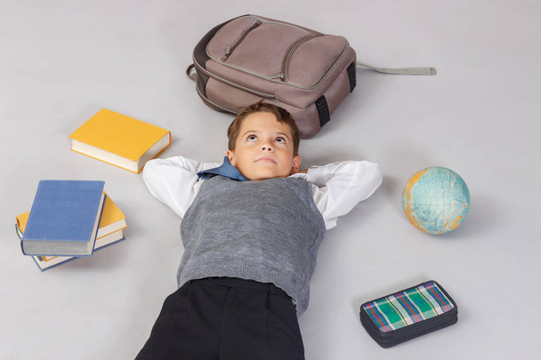 boy lying on the floor surrounded by school supplies hoping. - Photo, image
