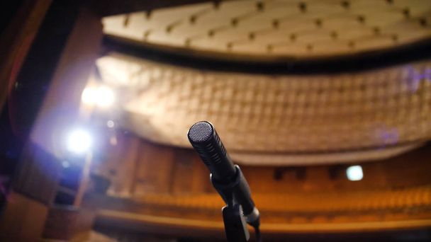 Mikrofon auf der Bühne und leerer Saal während der Probe. Mikrofon auf der Bühne mit Bühnenlicht im Hintergrund. Mikrofon auf der Bühne im leeren Saal - Foto, Bild