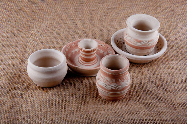 Artículos de cerámica. Tres barbas grises, plato y candelabro con patrones sobre fondo de saco marrón - Foto, imagen