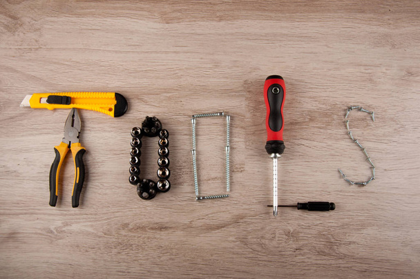 Herramientas de la palabra hechas por el equipo de reparación: destornillador, pinzas, cuchillo, alicates y tornillos que ponen en la mesa de madera - Foto, imagen