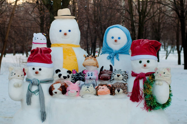 Фигуры четырех одетых снеговиков и снежных животных зимой остаются снаружи
 - Фото, изображение