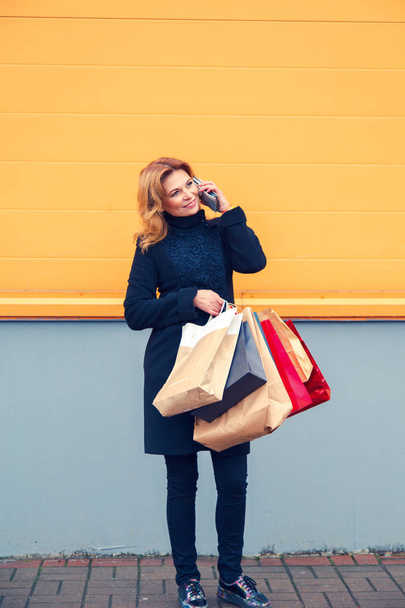 Beautiful woman with shopping bags talking on the phone. - 写真・画像