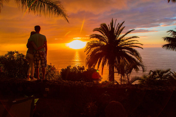 couple regardant coucher de soleil sur le bord de la falaise
 - Photo, image