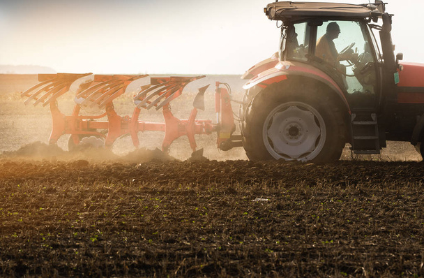 Traktor pflügt Felder um - Land für die Aussaat im Herbst vorbereiten - Foto, Bild