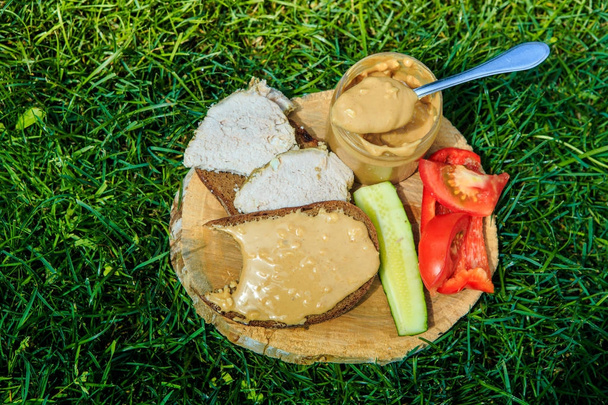 spoonful of peanut butter on wooden plate with meat sandwiches - Foto, afbeelding
