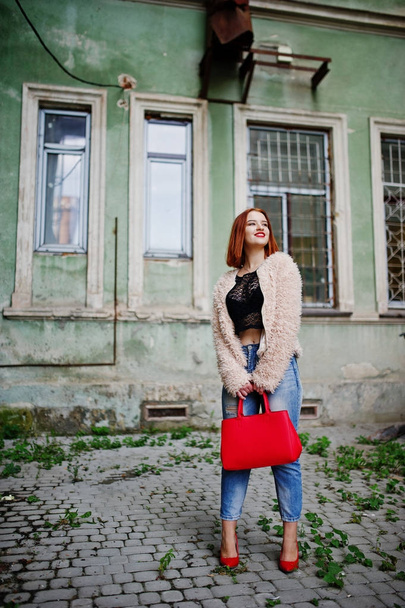 Red haired girl with red handbag posed at street of city. - Foto, imagen