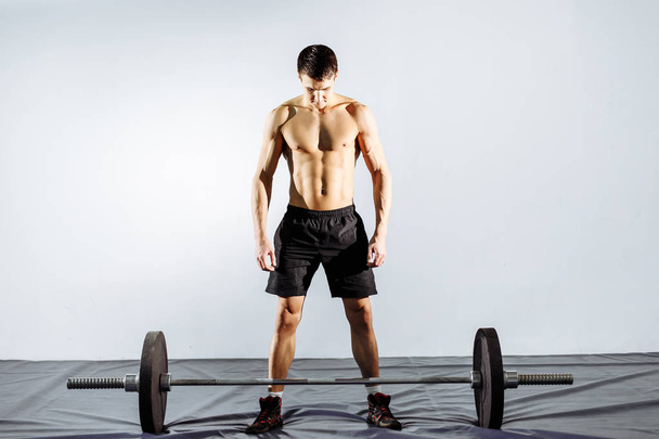 Muskularny mężczyzna ćwiczący na siłowni robi ćwiczenia ze sztangą, silny mężczyzna nagi tułów brzucha. - Zdjęcie, obraz