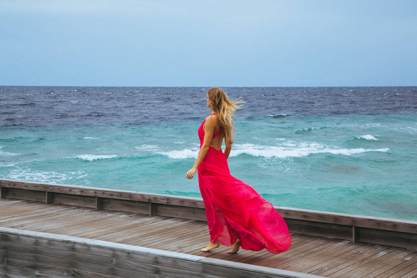 Girl in a long pink dress walking on the pier. - Foto, Bild