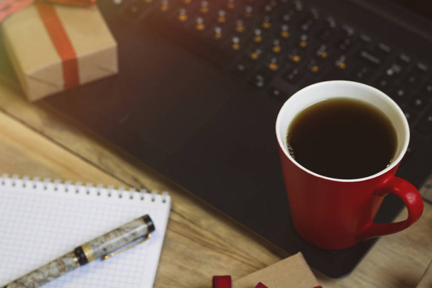 Arbeitsplatz mit Kaffee, Laptop, Weihnachtsgeschenken, Stift, Notizbuch - Foto, Bild