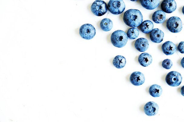 Freshly picked blueberries and spoon with blueberry on white, text space, top view. - Фото, зображення