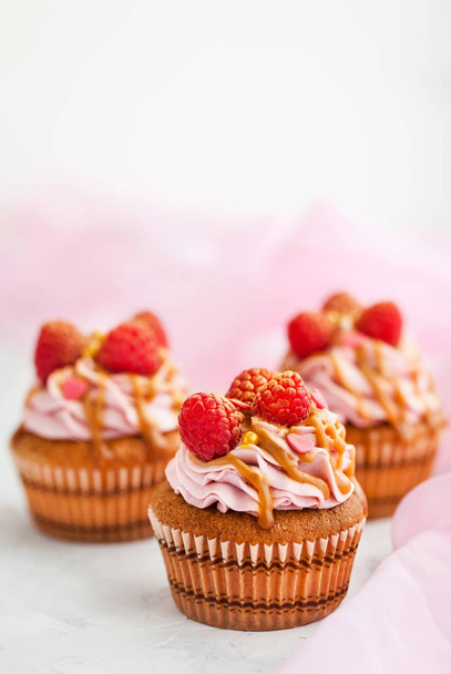 Framboesa e cupcakes de caramelo no fundo branco
 - Foto, Imagem