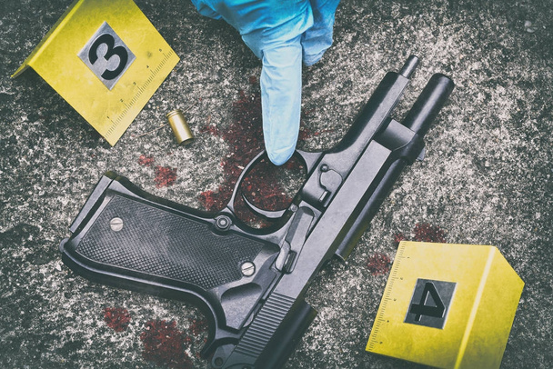 Przestępczości sceny dochodzenia, pistolet i bullet powłoki z plama krwi przeciwko przestępczości znacznik na ziemi. - Zdjęcie, obraz