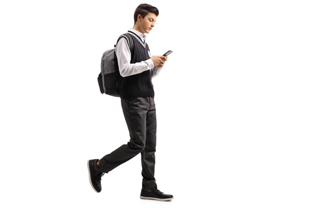 Teen student walking and using a phone - Foto, afbeelding