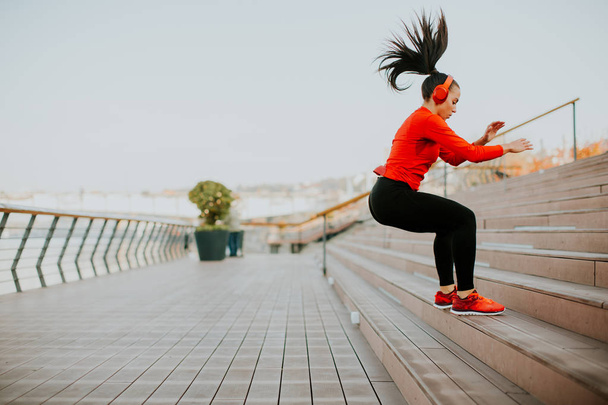Mujer joven haciendo ejercicio saltando afuera
 - Foto, imagen