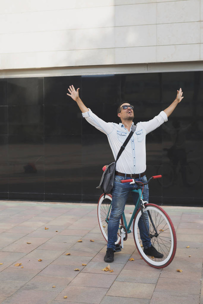 Urban man on a  bike with arms rise ( successful day ) - Foto, imagen