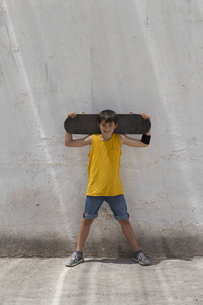 A teenage boy carrying skateboard and smiling - Фото, изображение