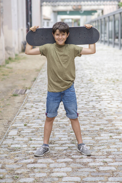 A teenage boy carrying skateboard and smiling - Photo, Image