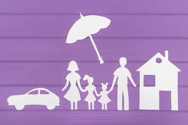 Силуэты вырезаны из бумаги мужчины и женщины с двумя девушками под зонтиком, дом и автомобиль рядом
 - Фото, изображение