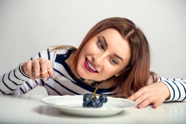 Retrato de una hermosa joven que está feliz por la comida. La muchacha observa la ración
 - Foto, imagen