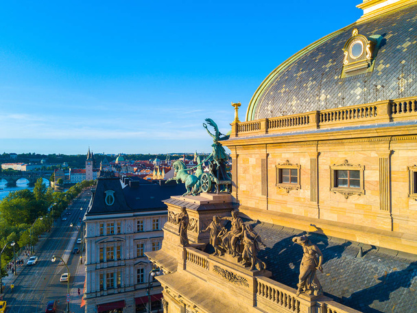 schöne Luftaufnahme des Prager Nationaltheaters entlang der Moldau. atemberaubender Blick auf das Theater bei Sonnenuntergang mit Pferdeskulpturen auf dem Dach. - Foto, Bild