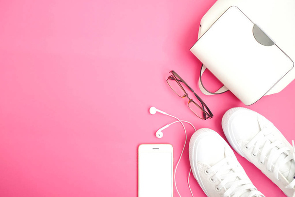 Feminine accessories flat lay. Woman shoes, bag, smartphone and watch on pink background. Beige color woman accessories. Text space. Top view.  White snickers on pink background. - Fotografie, Obrázek