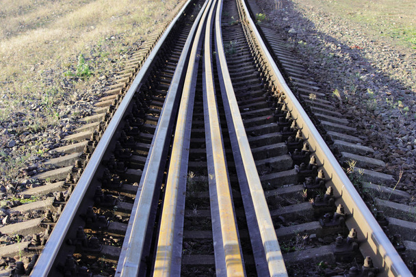 Verschillende rails liggen op de dwarsliggers tussen de belangrijkste rails op de spoorlijn. bouten die de rails op de dwarsliggers op de spoorlijn richting beveiligen - Foto, afbeelding