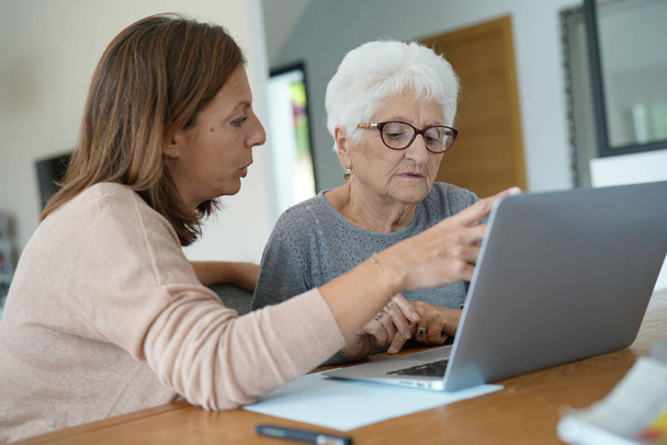 woman using laptop with help of homecarer - Φωτογραφία, εικόνα