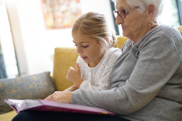 girl reading book with grandmother - Photo, Image