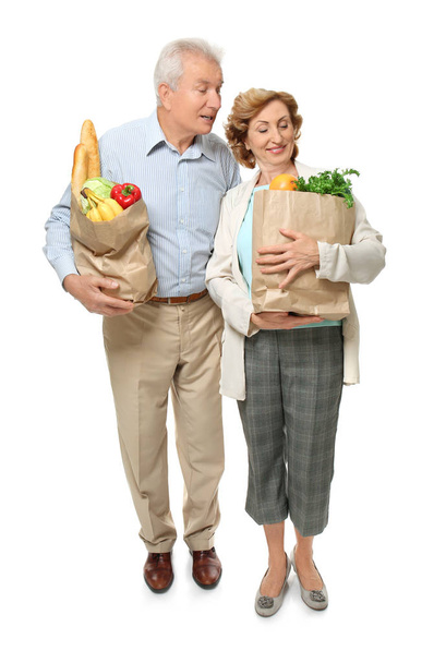 Elderly couple holding paper bags with groceries on white background - Фото, зображення