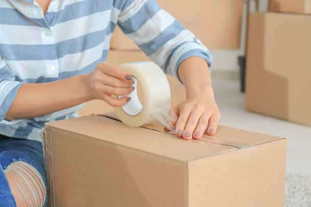 Young woman packing box, indoors - Foto, afbeelding