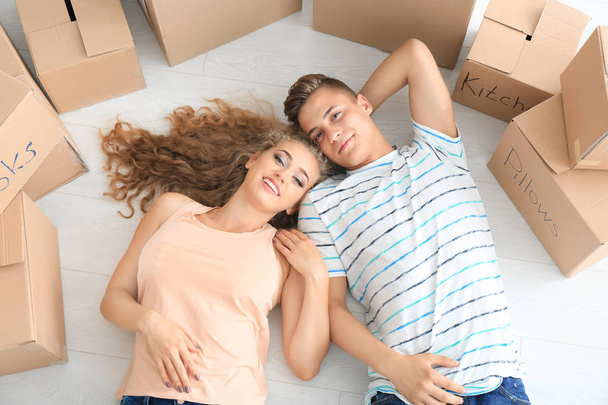 Jeune couple couché parmi des boîtes mobiles sur le sol
 - Photo, image