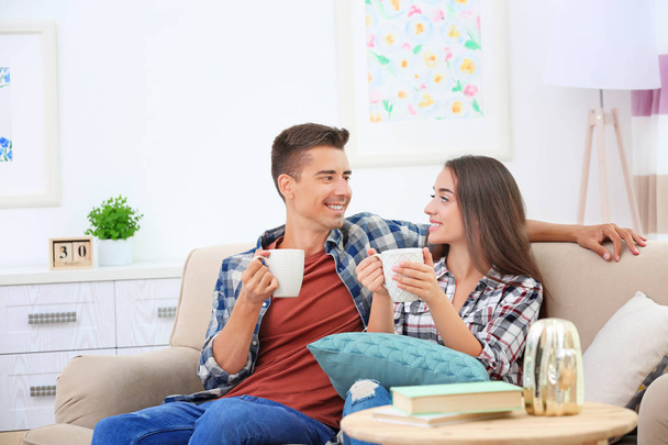 Young couple drinking tea on sofa at home - Фото, зображення