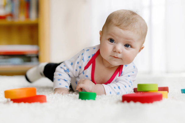 Söpö vauva tyttö leikkii värikäs puinen helistin lelu
 - Valokuva, kuva