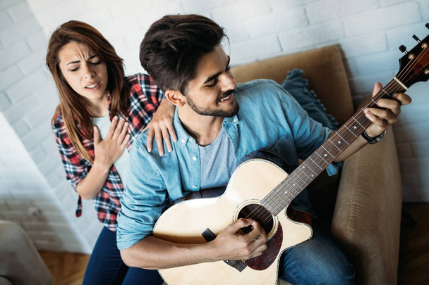  man playing guitar while  girlfriend is singing - Fotoğraf, Görsel