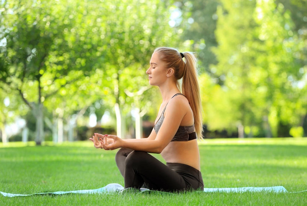 Sporty young woman doing yoga in park - Фото, зображення