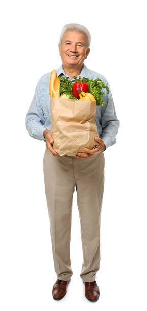 Elderly man holding paper bag with groceries on white background - Фото, зображення