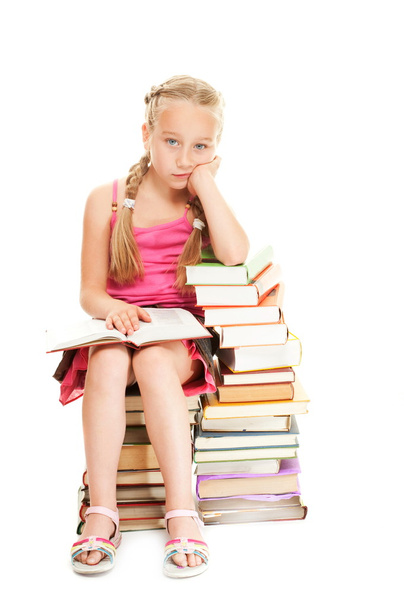 Pequeña colegiala sentada en libros
 - Foto, Imagen