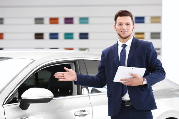Car salesman with tablet in dealership - Фото, изображение