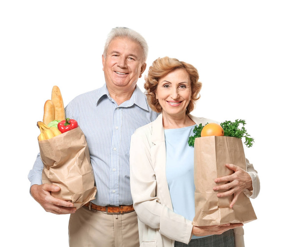 Elderly couple holding paper bags with groceries on white background - Foto, Imagen