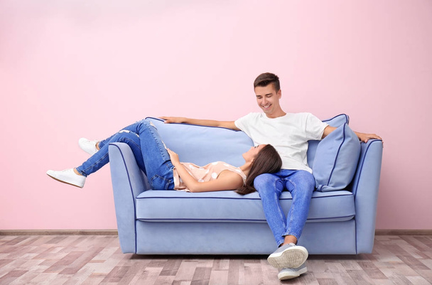 Young couple on blue sofa near color wall - Фото, зображення