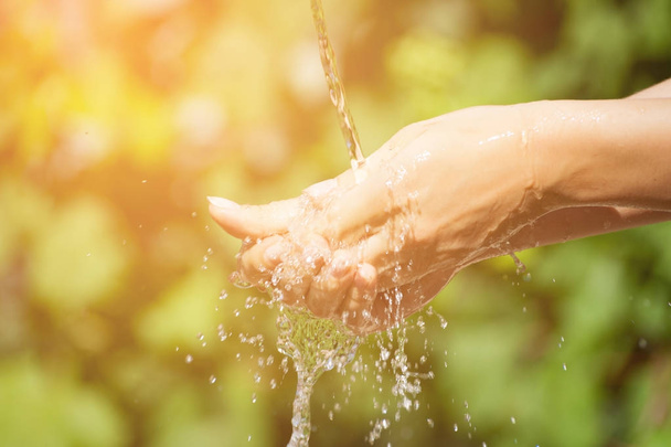 Donna che lava le mani all'aperto. Acqua potabile naturale nel palmo della mano
. - Foto, immagini