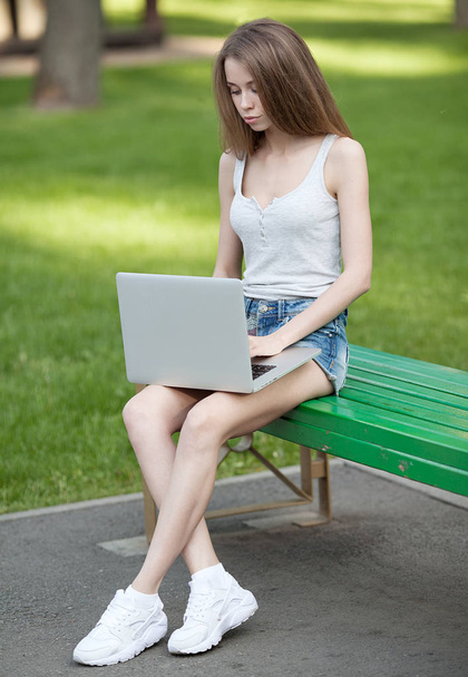 woman on the park sitting with a laptop computer in her lap and typing - Φωτογραφία, εικόνα