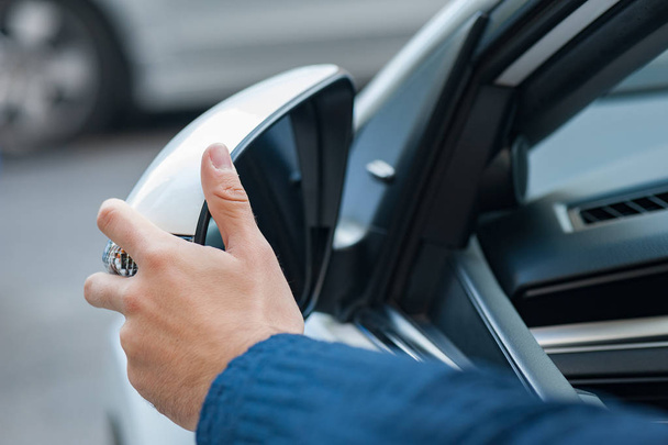 La main humaine prépare ou corrige le miroir de voiture pour le voyage ou le voyage depuis la fenêtre de la voiture
. - Photo, image